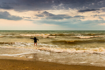 teenage girl jumping in the evening stormy sea, Azov sea, Ukraine