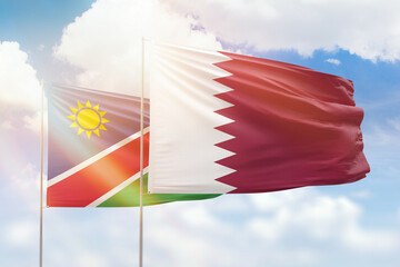 Sunny blue sky and flags of qatar and namibia