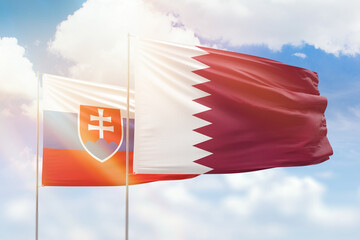 Sunny blue sky and flags of qatar and slovakia