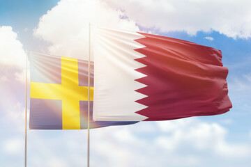 Sunny blue sky and flags of qatar and sweden