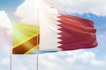 Sunny blue sky and flags of qatar and tanzania