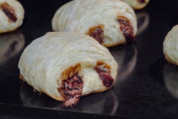 Mini puff pastry buns with chocolate filling baking and rising on tray in electric oven - close up view. Homemade bakery, food, cooking and pastry concept