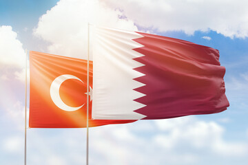 Sunny blue sky and flags of qatar and turkey