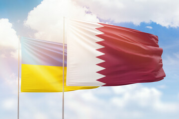 Sunny blue sky and flags of qatar and ukraine