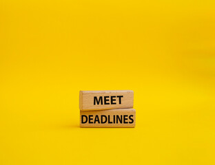 Meet Deadlines symbol. Concept word Meet Deadlines on wooden blocks. Beautiful yellowbackground....
