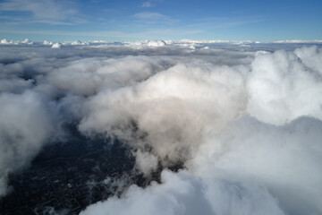 Aerial view from airplane window at high altitude of earth covered with puffy cumulus clouds...