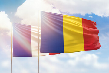 Sunny blue sky and flags of romania and france