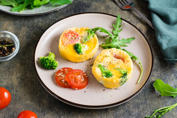 Portioned omelet from eggs, broccoli and tomatoes on a plate on the table. Homemade breakfast