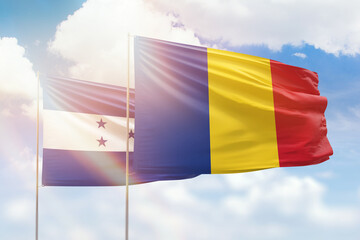 Sunny blue sky and flags of romania and honduras