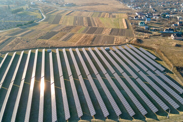 Fototapeta premium Aerial view of large sustainable electrical power plant with rows of solar photovoltaic panels for producing clean ecological electric energy. Renewable electricity with zero emission concept