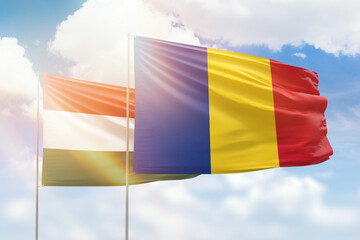 Sunny blue sky and flags of romania and hungary