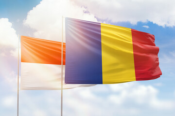 Sunny blue sky and flags of romania and indonesia