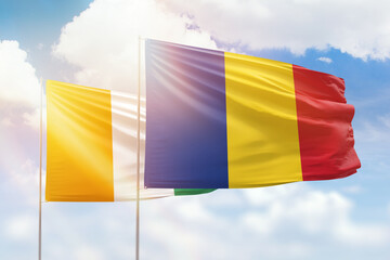 Sunny blue sky and flags of romania and ivory coast