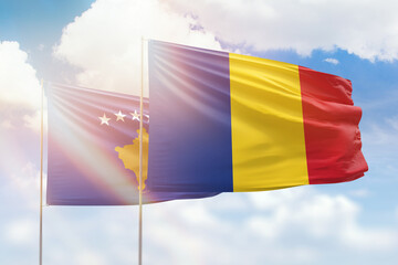 Sunny blue sky and flags of romania and kosovo