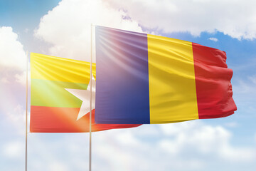 Sunny blue sky and flags of romania and myanmar