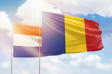 Sunny blue sky and flags of romania and paraguay