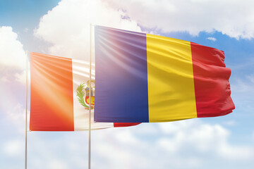 Sunny blue sky and flags of romania and peru