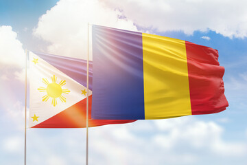Sunny blue sky and flags of romania and philippines
