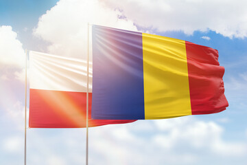 Sunny blue sky and flags of romania and poland