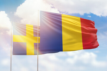 Sunny blue sky and flags of romania and sweden