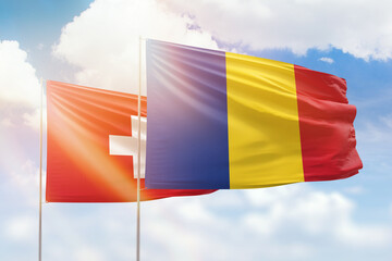 Sunny blue sky and flags of romania and switzerland