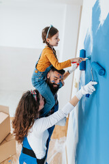Happy family renovating their home. They are painting a wall together.