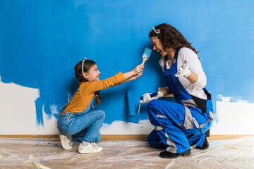 Mother and daughter enjoying together while painting wall. - 511946714