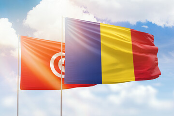 Sunny blue sky and flags of romania and tunisia