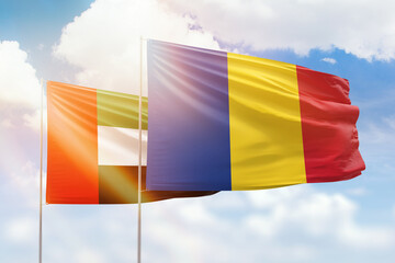 Sunny blue sky and flags of romania and uae