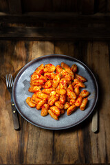 Italian potato Gnocchi with tomato sauce. Rustic style, wooden background