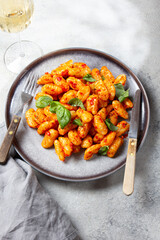 Traditional Italian potato Gnocchi with tomato sauce and fresh basil on gray plate, marbled backround.
