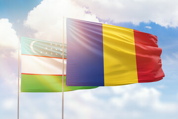 Sunny blue sky and flags of romania and uzbekistan