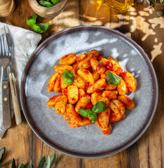 Italian Gnocchi with tomato sauce and basil on wooden background