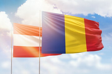 Sunny blue sky and flags of romania and austria
