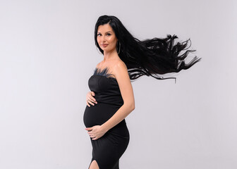 Cropped of pretty female embracing pregnant belly, having prifessional makeup wand wavy long hair,...