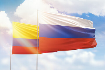Sunny blue sky and flags of russia and colombia