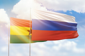 Sunny blue sky and flags of russia and ghana