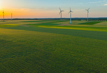 Aerial drone view of wind power turbines, part of a wind farm. Wind turbines on green field in...