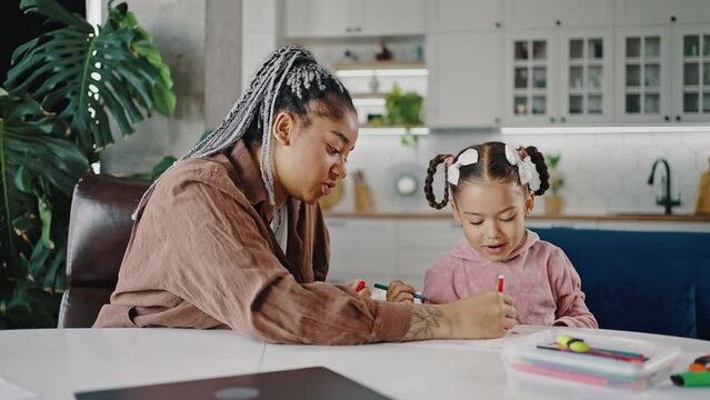 Young african american mother and daughter drawing picture together at home, tracking shot, slow motion