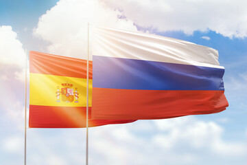 Sunny blue sky and flags of russia and spain