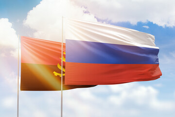 Sunny blue sky and flags of russia and angola