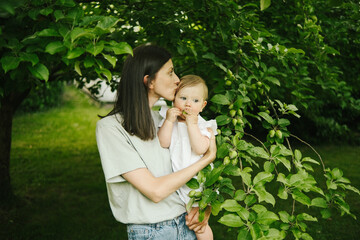 mom with baby in her arms near the fruit tree