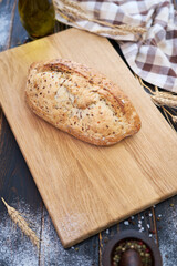 Fresh bread loaf on wooden cutting board at kitchen table