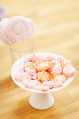 Small freshly made meringues on plate and meringue pops in glass, sweet candies background