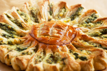 Delicious pie with spinach and ricotta cheese in the shape of a sunflower, close-up.