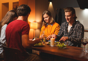 Group of four young friends, two couples, having dinner with candles together during double date at home