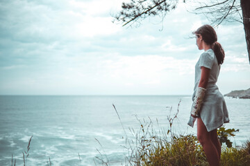 Chica mirando hacia el mar desde la montaña.