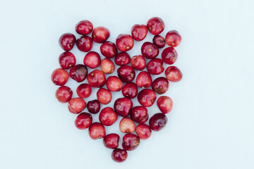 Sweet red cherries on a white background in the shape of an heart. Ripe fresh red sweet cherry isolated on white background