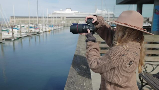 Portrait of a woman enjoying her photos at the docks. Charming coastal town with boats and yachts and female tourist observing panoramic views. High quality 4k footage