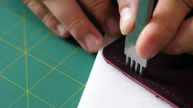 The man pierces the skin with punches making a hole for sewing threads. Punching frame close up.